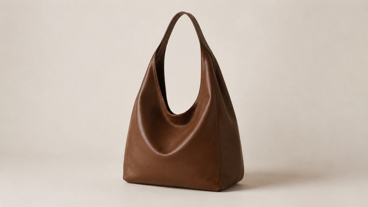 Leather hobo bag against a plain warm off-white wall