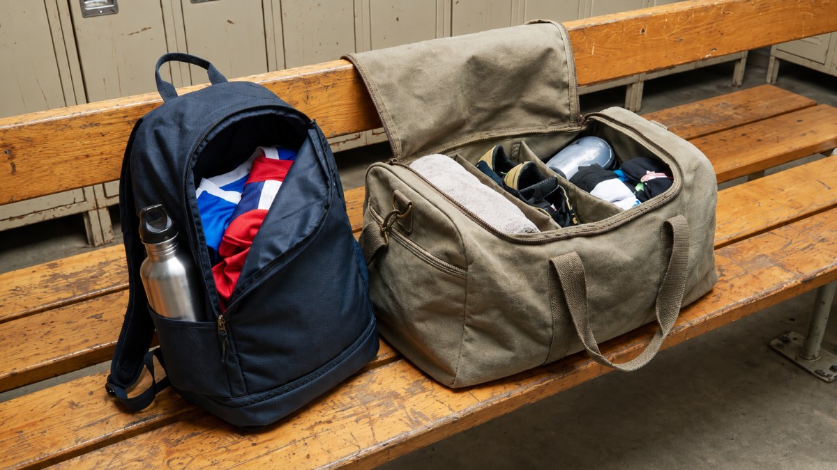 Soccer backpack and duffle bag side by side on locker-room bench