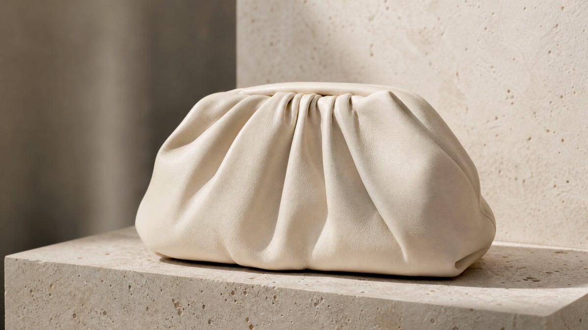 Cream pleated lambskin pouch bag displaying soft drape and supple fine-grain leather texture.