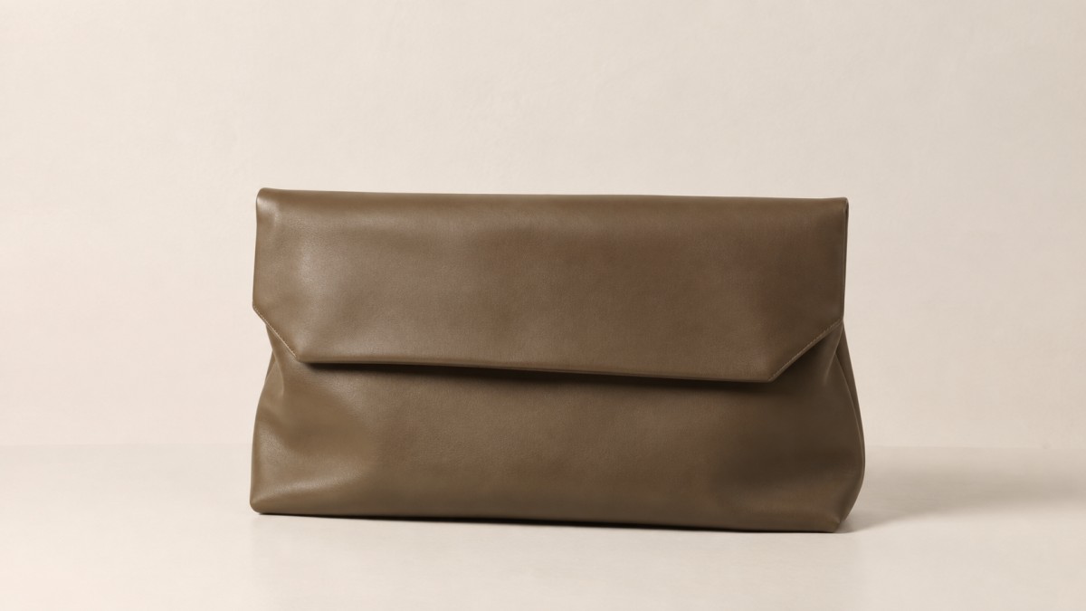 Leather clutch against a plain warm off-white wall